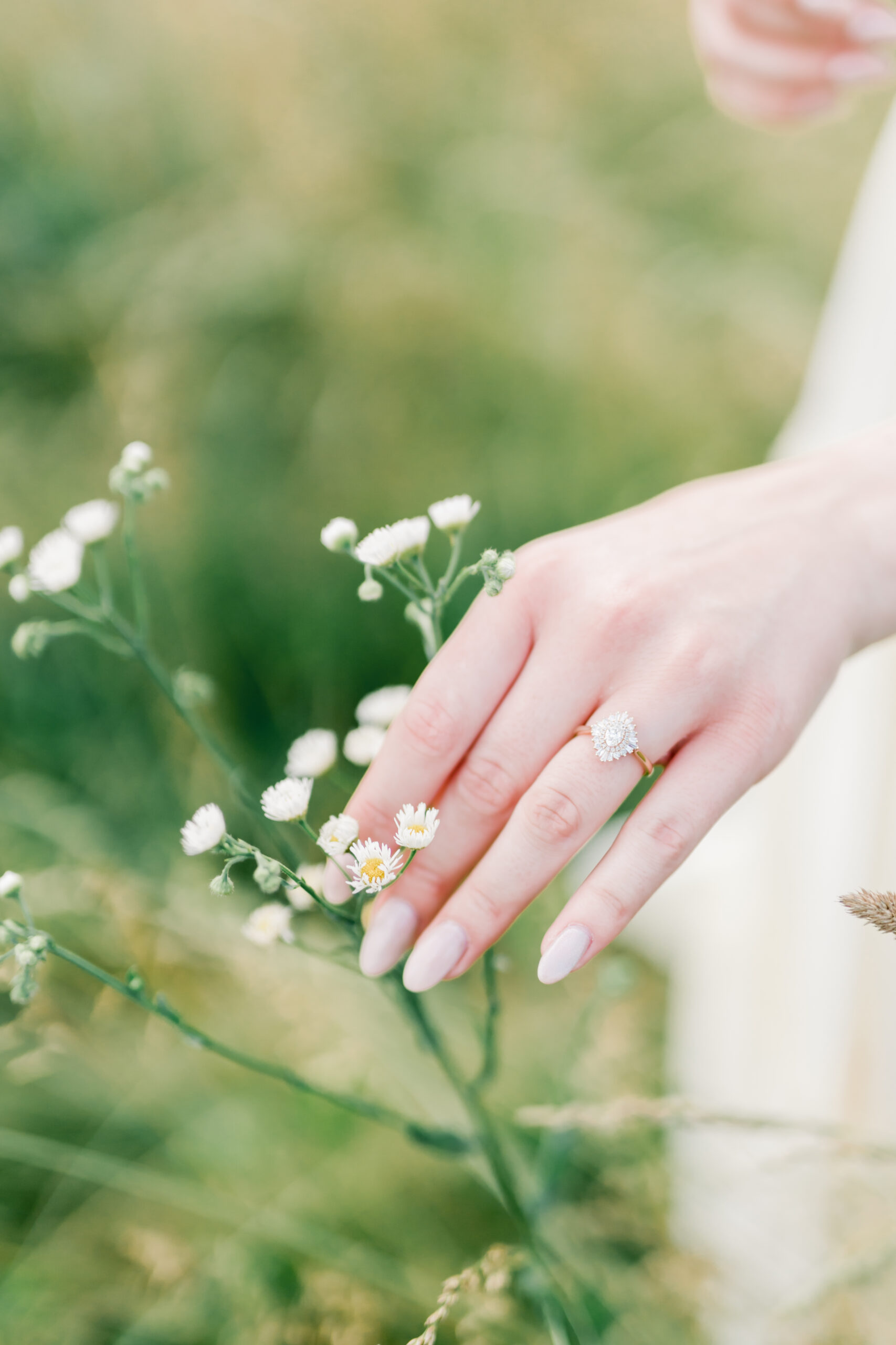 Woman holding small white flowers with engagement ring showing prominently