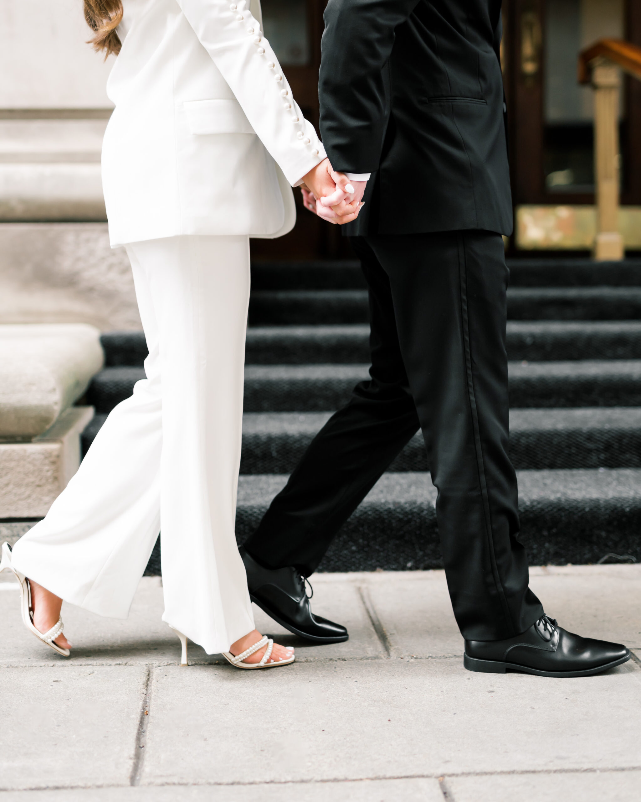 Woman wearing white walking with man wearing black suit